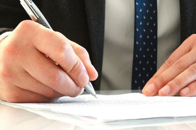 man holding a pen signing a paper