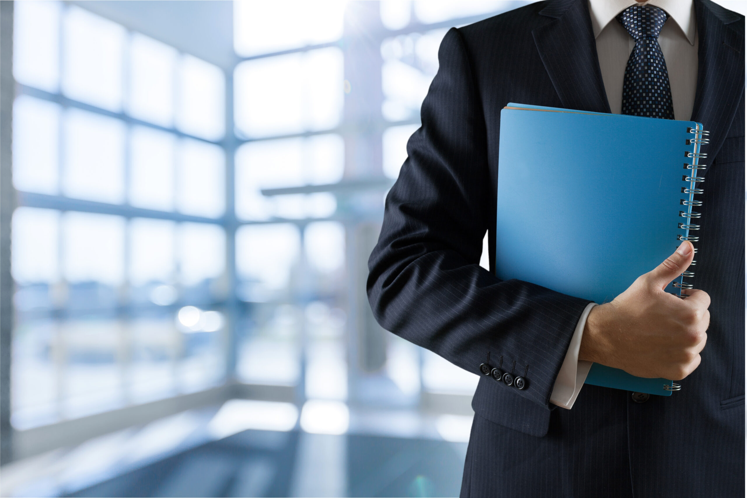 Business man holding a blue folder in an office setting