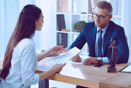 lawyer and client looking at each other while discussing papers in office