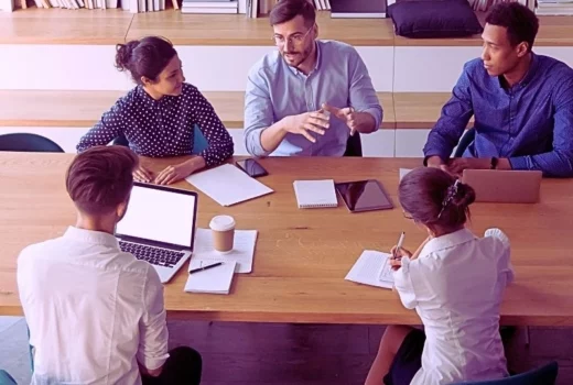 Businesspeople sitting at desk gathered in modern board room