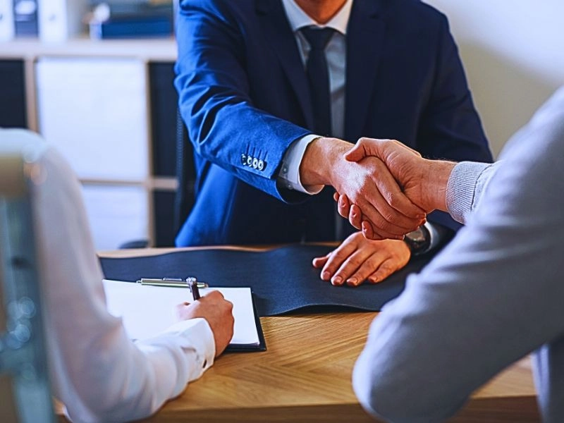 Male lawyer shaking hands with a make client with his wife beside him. recruitment process for lawyers
